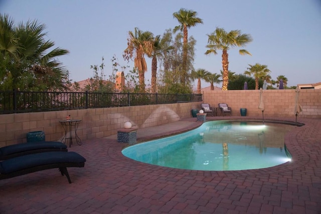 pool at dusk featuring a patio area