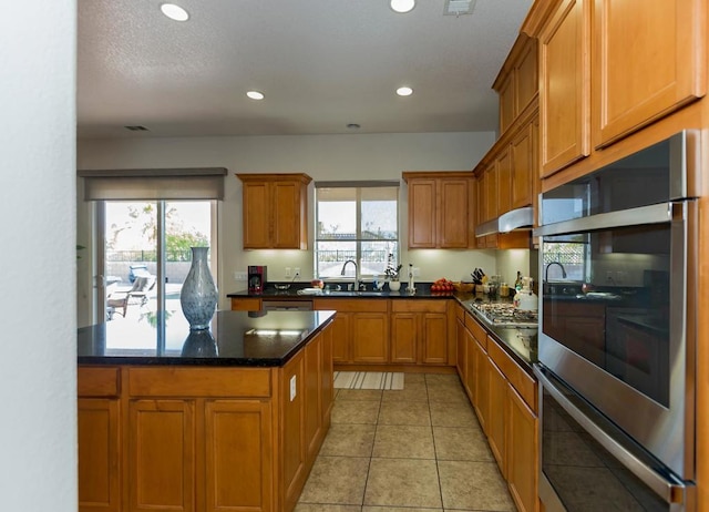 kitchen with sink, light tile patterned floors, a healthy amount of sunlight, and appliances with stainless steel finishes