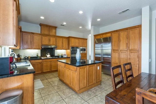 kitchen with built in appliances, sink, a kitchen island, and light tile patterned floors