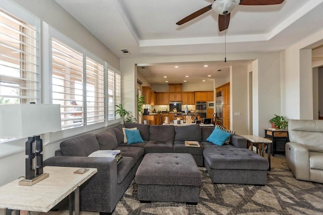 living room featuring a raised ceiling and ceiling fan