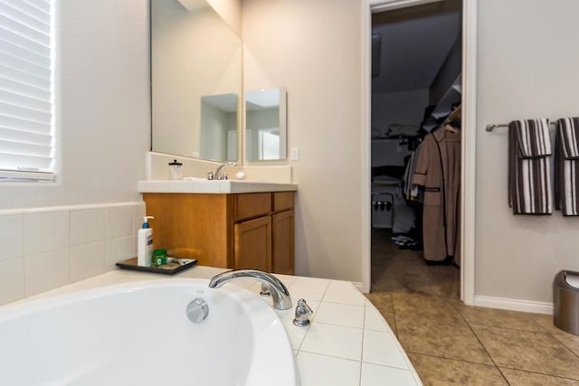 bathroom featuring tile patterned flooring, vanity, and a washtub