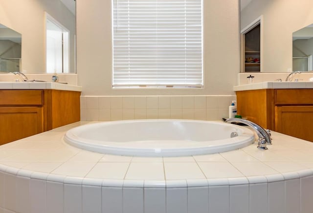 bathroom featuring tiled bath and vanity