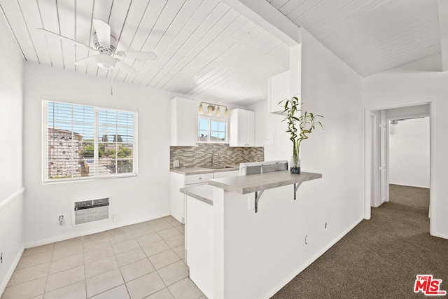 kitchen with a breakfast bar, sink, white cabinetry, kitchen peninsula, and light tile patterned floors