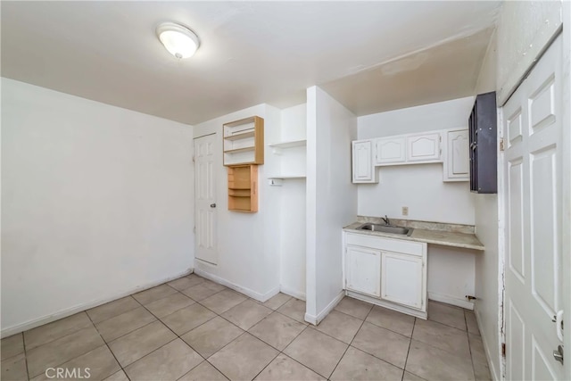 kitchen with light tile patterned floors, sink, and white cabinetry