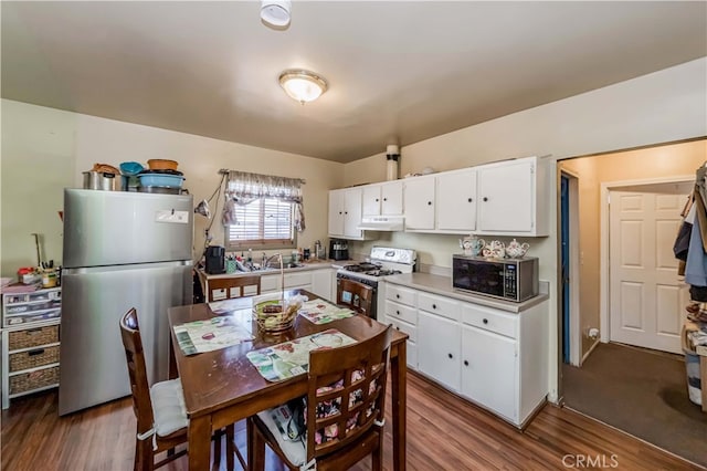 kitchen with range with gas stovetop, white cabinetry, dark wood-type flooring, and stainless steel refrigerator