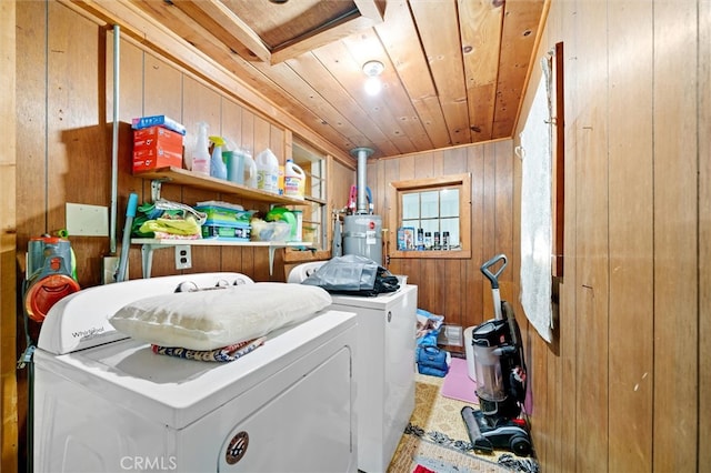 washroom featuring washing machine and clothes dryer, wood ceiling, wood walls, and gas water heater