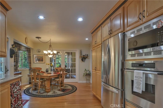 kitchen with pendant lighting, stainless steel appliances, french doors, a chandelier, and light wood-type flooring