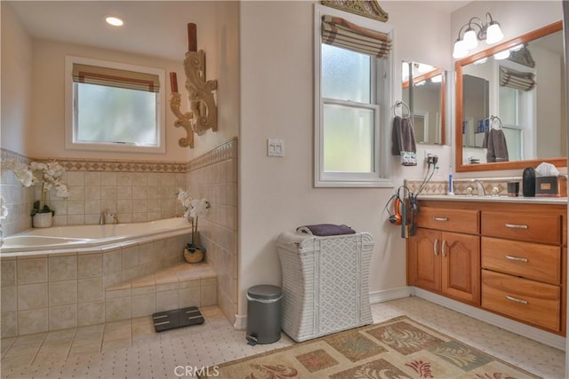 bathroom featuring tiled tub and vanity