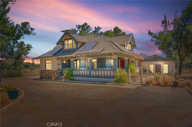 view of front of home featuring covered porch and solar panels