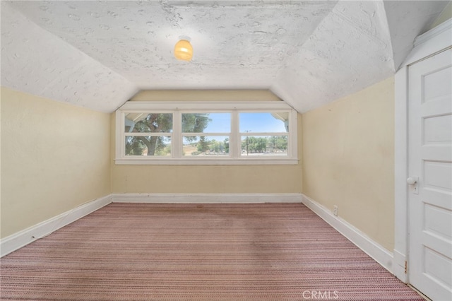 additional living space with a textured ceiling, carpet, and lofted ceiling