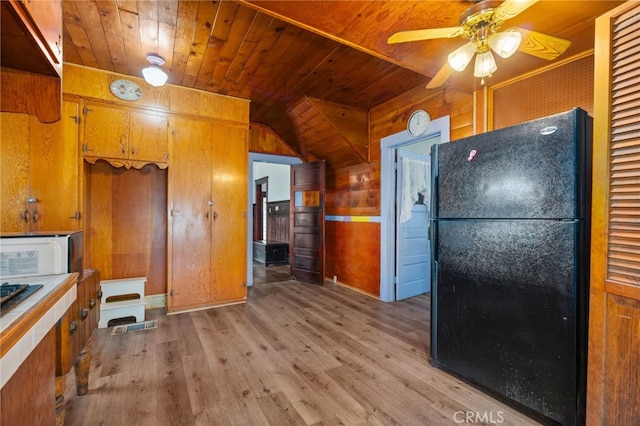 kitchen featuring wood ceiling, black refrigerator, wood walls, light wood-type flooring, and ceiling fan