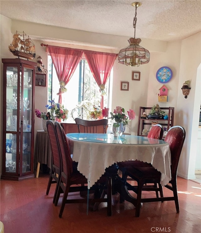 dining space with a notable chandelier, hardwood / wood-style floors, and a textured ceiling