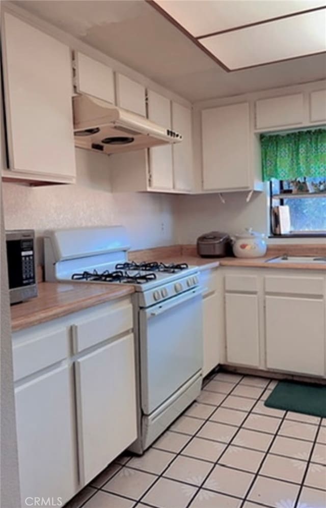 kitchen featuring light tile patterned floors, white cabinetry, and white gas stove