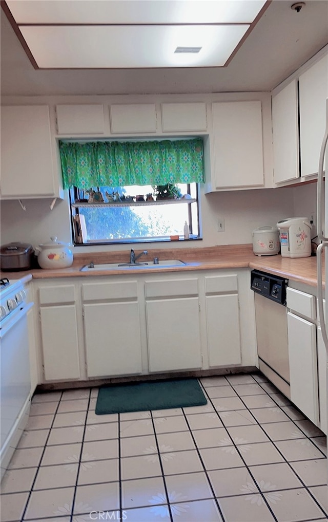 kitchen featuring white cabinets, white appliances, light tile patterned floors, and sink