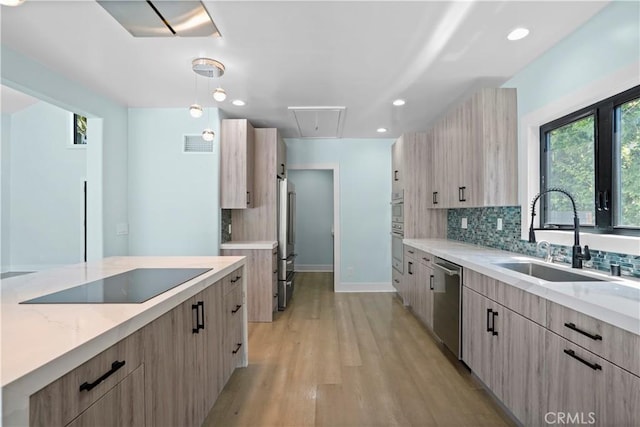 kitchen with sink, light hardwood / wood-style flooring, backsplash, light brown cabinetry, and appliances with stainless steel finishes