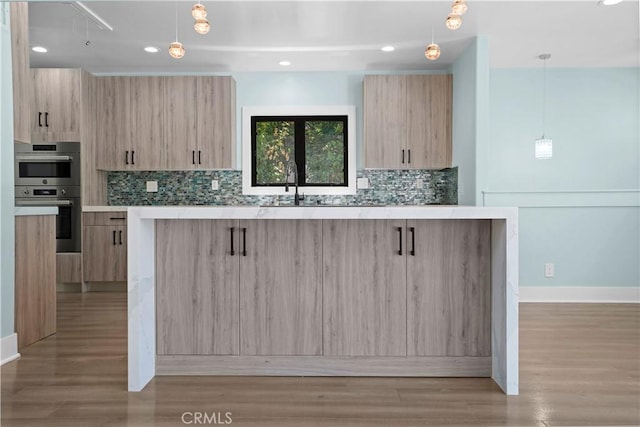 kitchen with light brown cabinets, light wood-type flooring, and hanging light fixtures