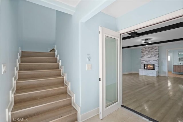 stairway featuring a stone fireplace and hardwood / wood-style floors