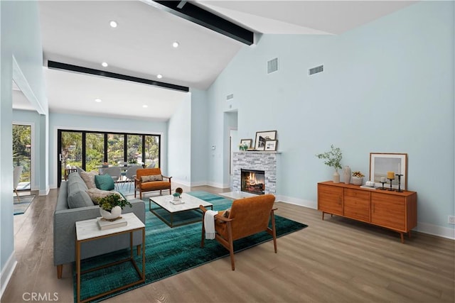 living room with beamed ceiling, wood-type flooring, high vaulted ceiling, and a fireplace