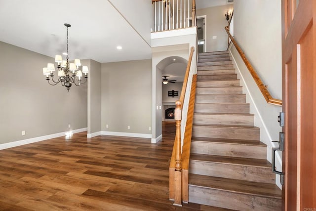 staircase featuring hardwood / wood-style floors and ceiling fan with notable chandelier