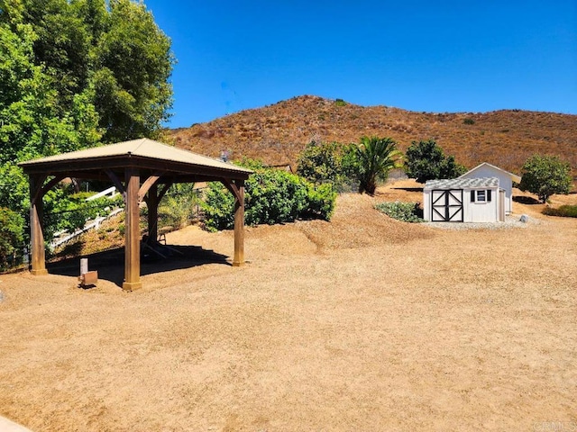 view of yard featuring a mountain view, a gazebo, and a storage unit