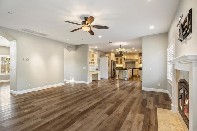 unfurnished living room featuring ceiling fan with notable chandelier and dark wood-type flooring