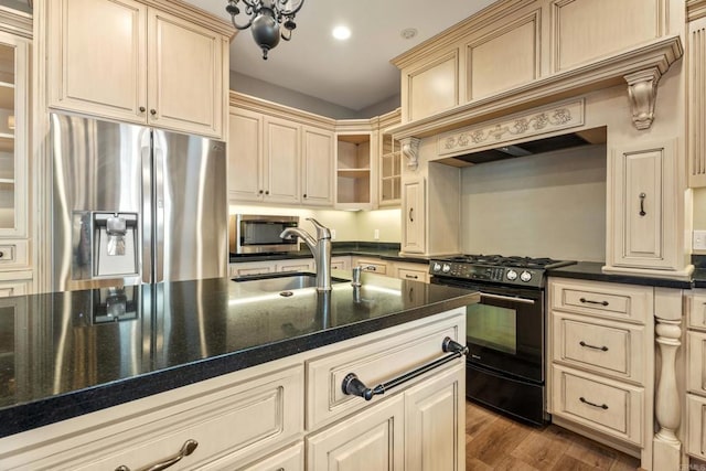 kitchen featuring stainless steel fridge, black stove, sink, wood-type flooring, and dark stone countertops