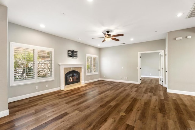 unfurnished living room with ceiling fan, a fireplace, and dark wood-type flooring