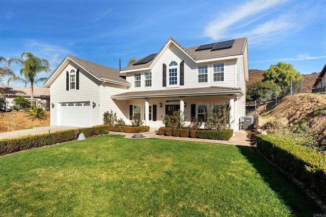 front of property featuring a front yard, solar panels, a porch, and a garage