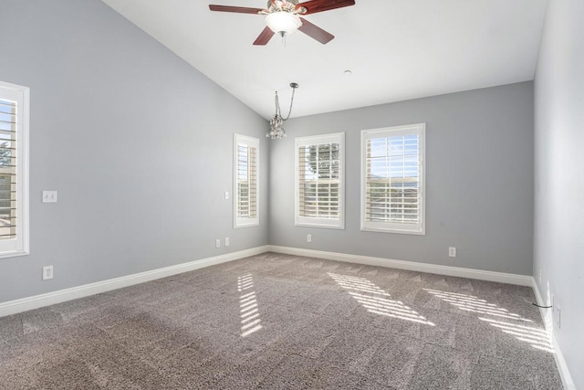 carpeted spare room with ceiling fan with notable chandelier and lofted ceiling