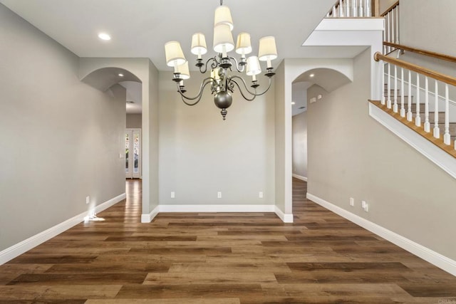 unfurnished dining area with dark wood-type flooring and a notable chandelier