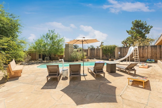 view of swimming pool with a water slide and a patio