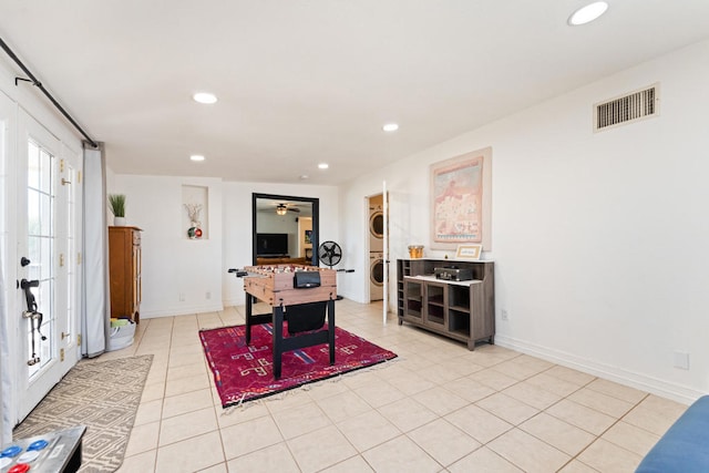 tiled office space featuring stacked washer and clothes dryer and ceiling fan