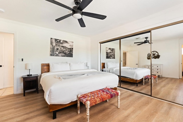 bedroom with a closet, hardwood / wood-style flooring, crown molding, and ceiling fan