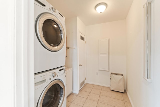 washroom with stacked washer / dryer and light tile patterned flooring