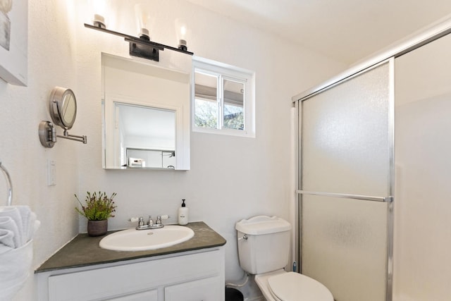 bathroom with toilet, a shower with shower door, and vanity