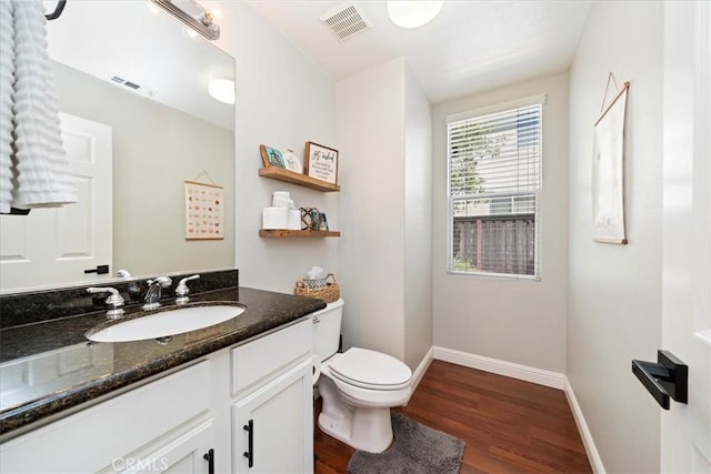 bathroom featuring toilet, wood finished floors, vanity, visible vents, and baseboards