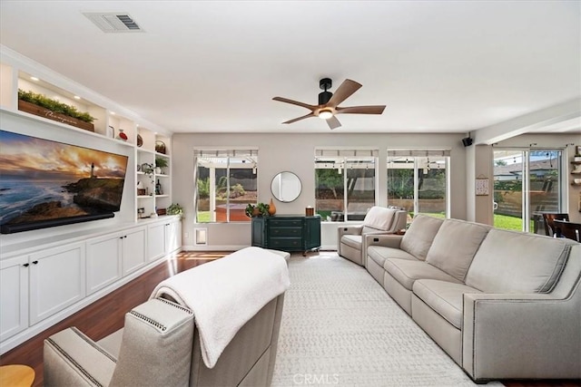 living room featuring plenty of natural light, wood finished floors, visible vents, and built in features