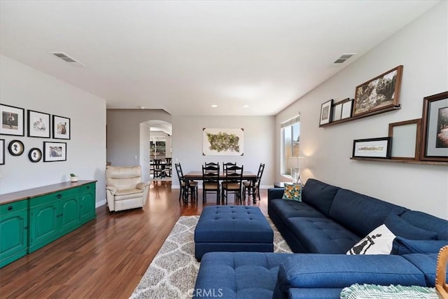 living area with baseboards, visible vents, and dark wood-style flooring