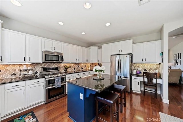 kitchen featuring dark wood-style floors, appliances with stainless steel finishes, a kitchen island, and white cabinetry