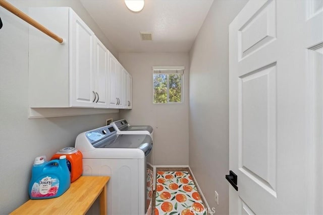 washroom featuring visible vents, washing machine and dryer, cabinet space, and baseboards