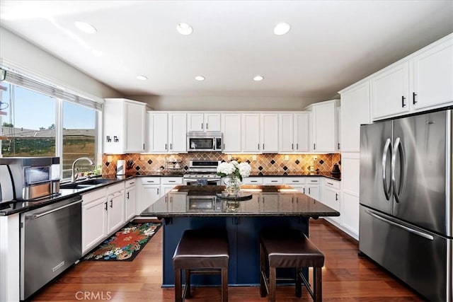 kitchen with stainless steel appliances, tasteful backsplash, a sink, and a center island