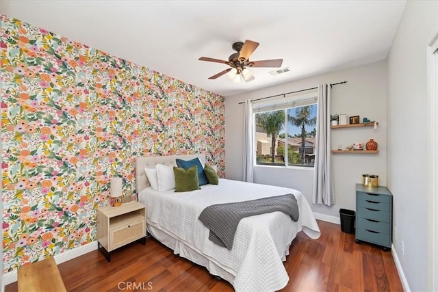 bedroom with wallpapered walls, dark wood finished floors, visible vents, and baseboards