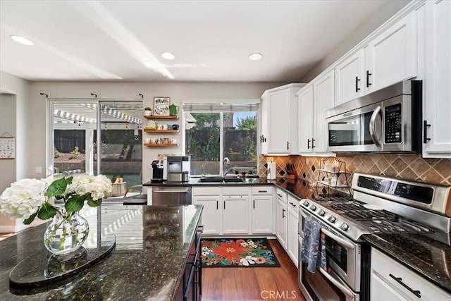 kitchen featuring white cabinets, appliances with stainless steel finishes, decorative backsplash, and a sink