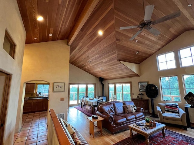 living room featuring ceiling fan, a towering ceiling, wood ceiling, and light wood-type flooring