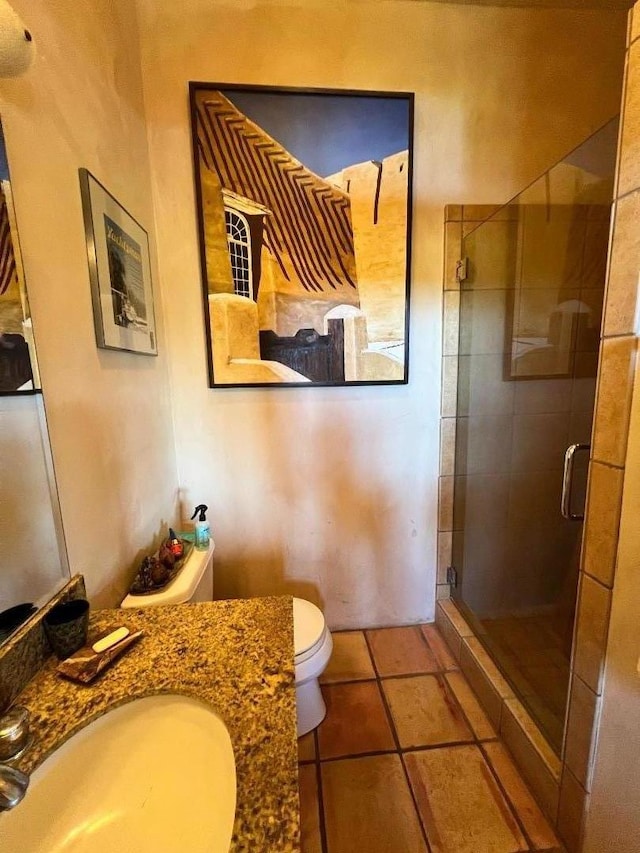 bathroom featuring tile patterned floors, toilet, an enclosed shower, and vanity