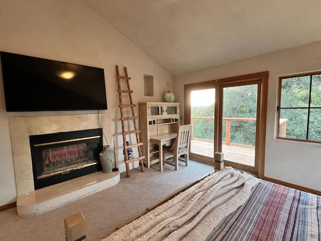 carpeted bedroom featuring a tiled fireplace, vaulted ceiling, and access to exterior