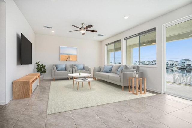 tiled living room with a water view and ceiling fan