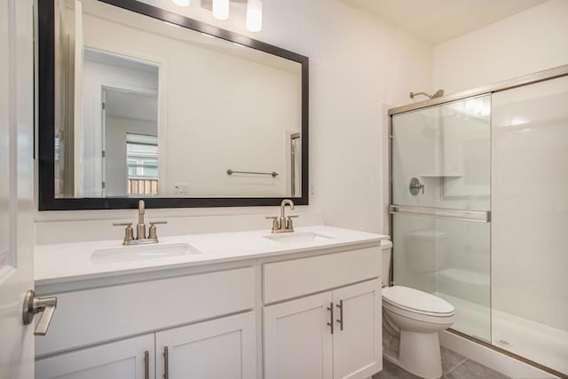 bathroom featuring tile patterned flooring, vanity, toilet, and a shower with door