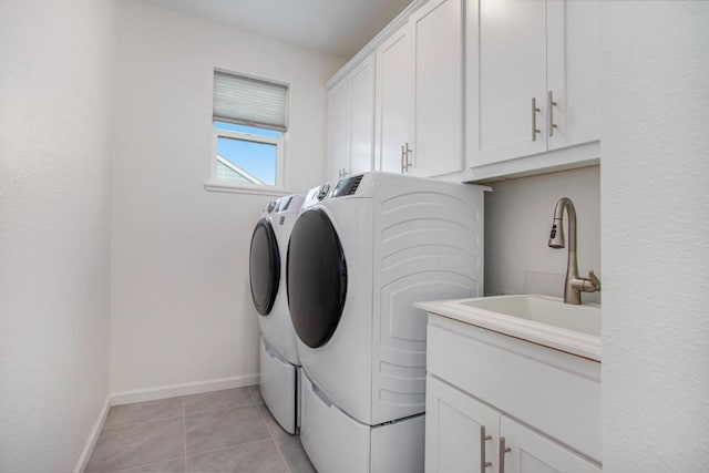 laundry area with washing machine and clothes dryer, sink, light tile patterned flooring, and cabinets