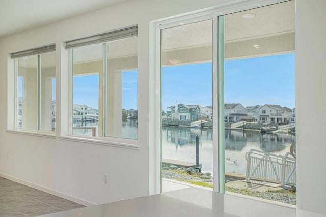 doorway to outside featuring a wealth of natural light, tile patterned flooring, and a water view